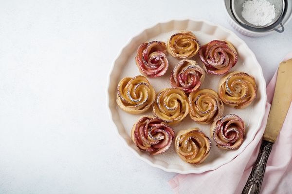 Розочки из слоёного теста с яблоками delicious pies with an apple rose in ceramic form on a light concrete or stone surface selective focus top view 1 - Розочки из слоёного теста с яблоками
