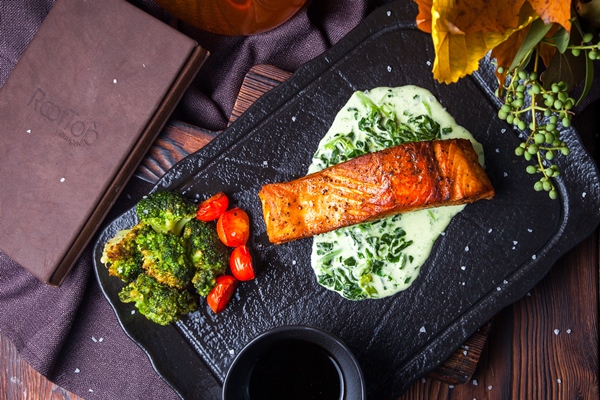 Филе сёмги в соусе из сладкого перца top view delicious meal in black tray on dark wooden background with decorations - Филе сёмги в соусе из сладкого перца