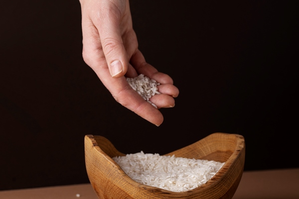 hand holding rice from bowl zakat concept - title=