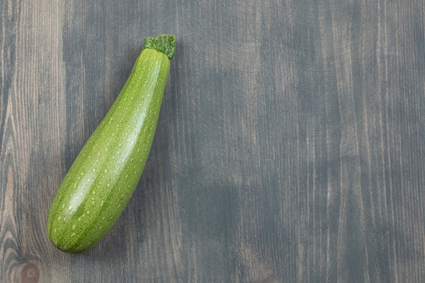 single courgette or zucchini isolated on a wooden table 1 - Кугель овощной в мультиварке