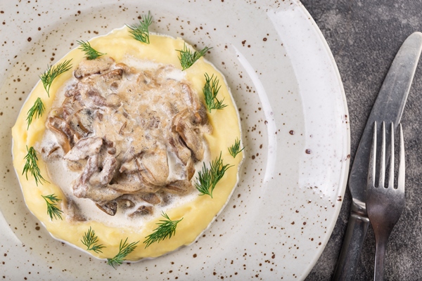 beef stroganoff with mashed potatoes white plate with cutlery - Филе кролика в сметане с картофельным пюре