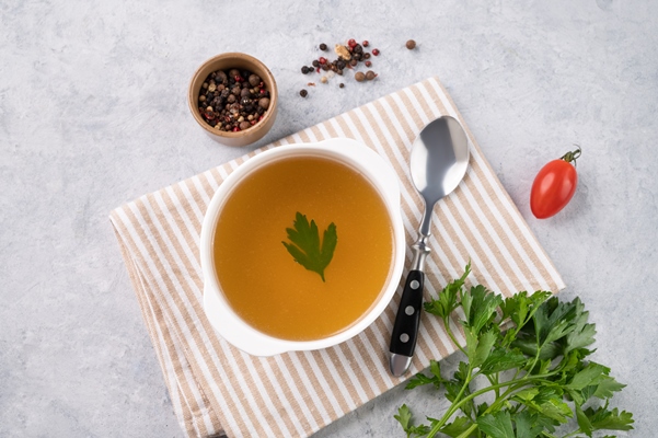 meat broth with parsley white plate light background with fresh herb spoon napkin concept healthy diet food top view copy space - Овощной бульон
