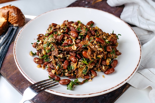 Лобио рюмили front view fried beans along with greens inside white plate brown wooden desk surface - Лобио рюмили