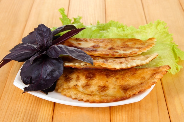 tasty chebureks with fresh herbs plateon wooden background - Постные чебуреки с чечевицей