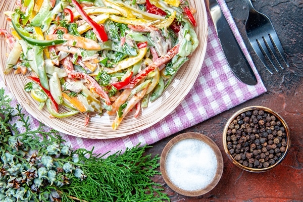 top view vegetable salad plate tablecloth fork knife salt black pepper pine branches dark red table - Салат из солёных огурцов и болгарского перца