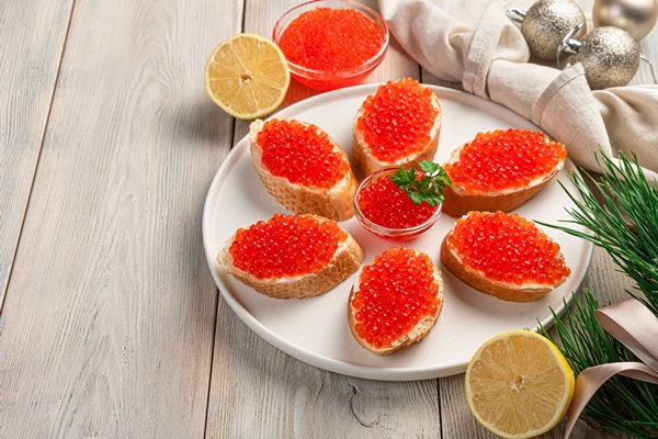 dish with sandwiches with red caviar light christmas background - Лучшие рецепты быстрой засолки икры в домашних условиях