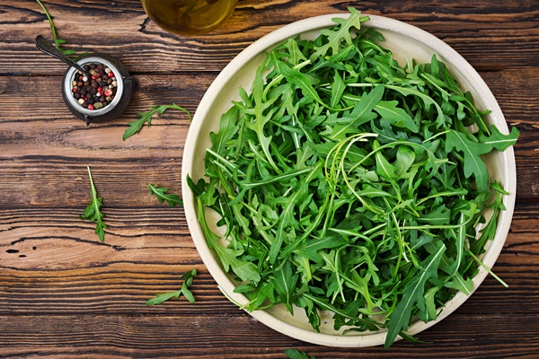 fresh leaves arugula bowl wooden background flat lay top view - Рукола