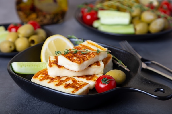 grilled haloumi cheese black pan with olives tomatoes cucumbers pepperoni close up - Адыгейский сыр на гриле