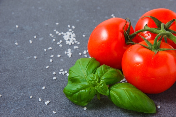 close up bunch of tomatoes with leaves on gray surface horizontal - Постная шаурма с тофу, помидорами и базиликом
