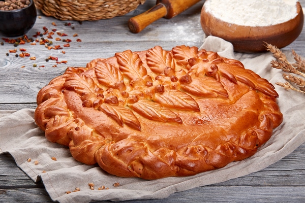 real appetizing homemade pie with potatoes gray linen towel gray wooden background with golden braid crust carved leaves with berries - Постный пирог с перловой крупой и солёными огурчиками