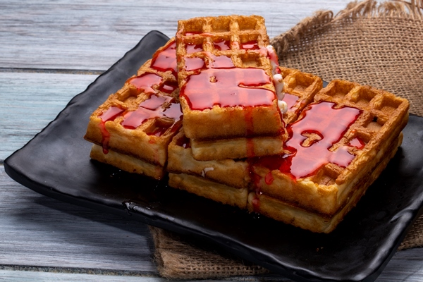 side view waffles with strawberry syrup black platter - Вафли постные из тофу