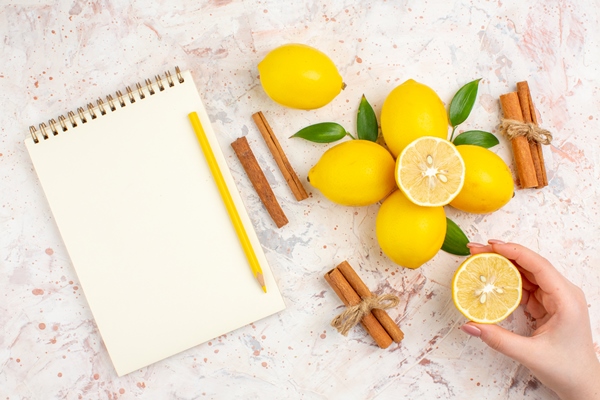Лимонная начинка для пирогов top view fresh lemons cut lemon in female hand cinnamon sticks yellow pencil in female hand on bright isolated surface - Лимонная начинка для пирогов