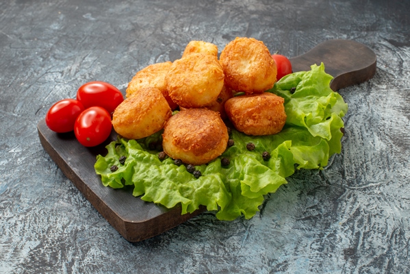 bottom view fried cheese balls cherry tomatoes lettuce cutting board grey background - Картофельные зразы с соевым фаршем